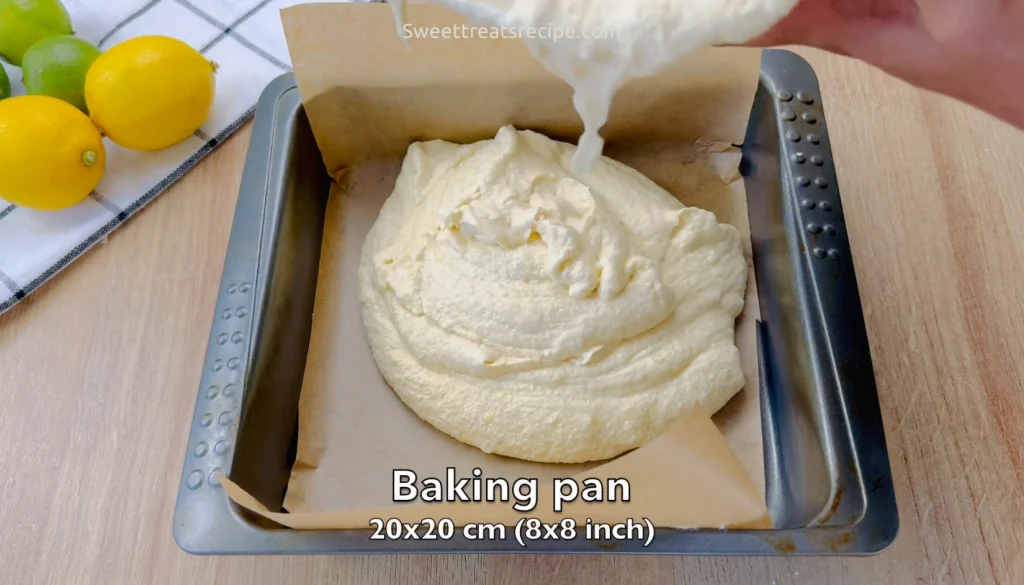 Lemon batter being poured into a 20x20 cm (8x8 inch) square pan lined with parchment paper, ready for baking.