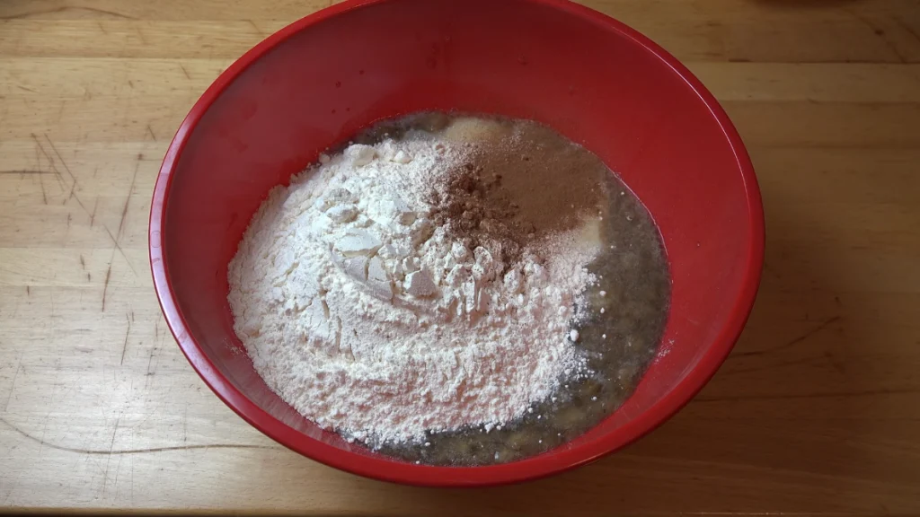 Dry and wet ingredients in a red bowl before mixing for banana bread.