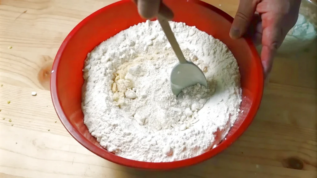 Mixing dry and wet ingredients by hand in a red bowl for banana bread.