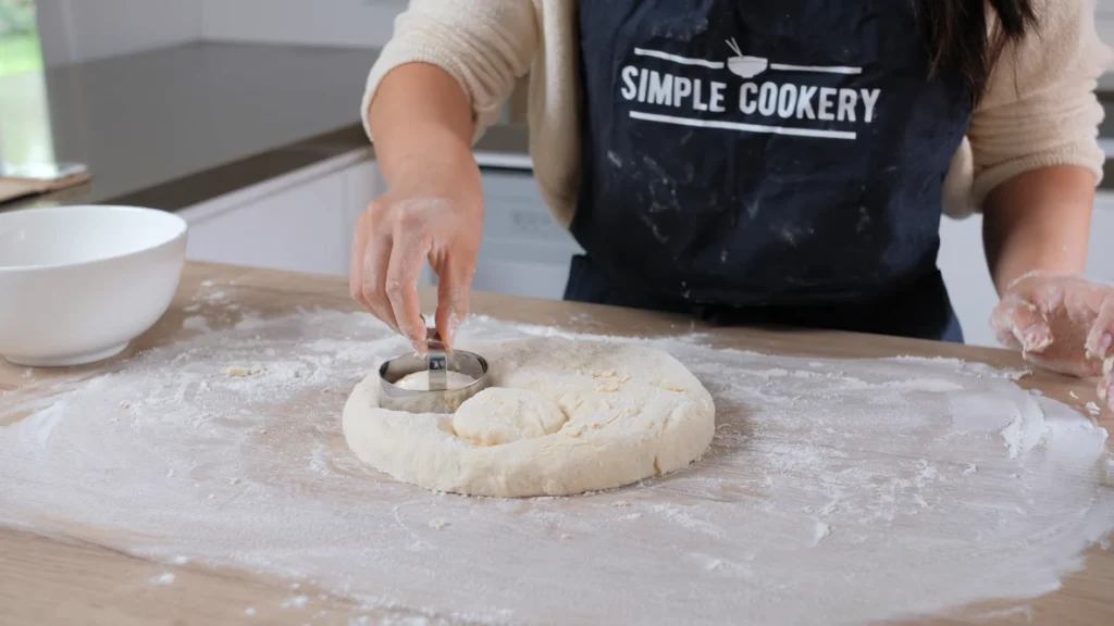 Using a round scone cutter to press down into the dough without twisting, forming even, round scones ready for baking.