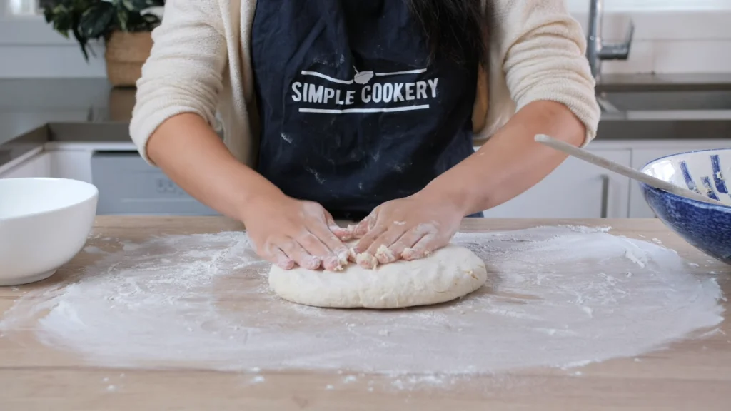  Lightly kneading the scone dough on a floured surface to prevent overworking. The dough is formed into a one-inch thick disc.